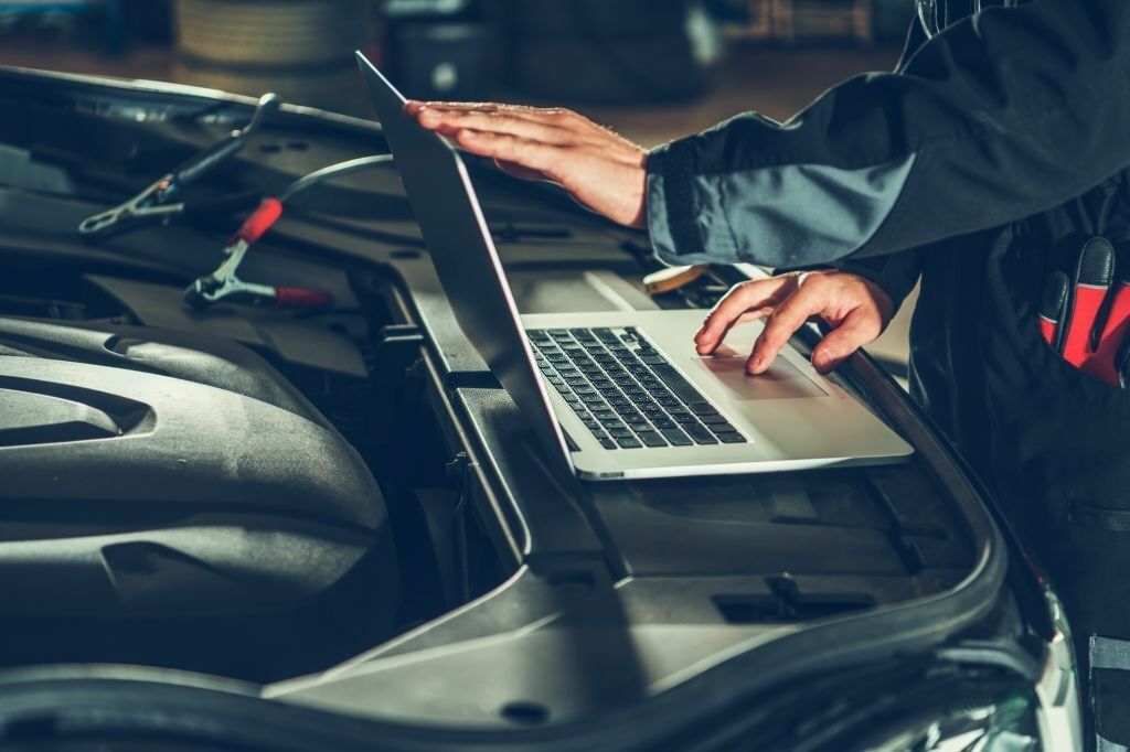 Auto mechanic or auto technician diagnosing car using a laptop