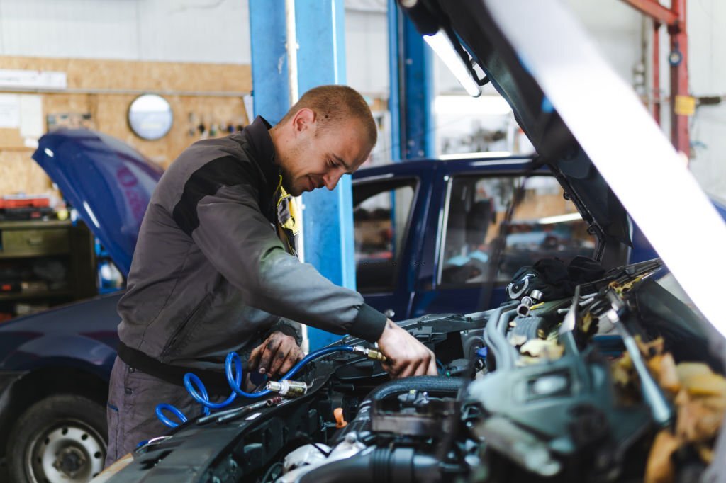 Auto mechanic in uniform is working in auto service garage. Repair service.